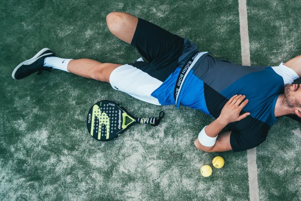 Tennis player laying on the court.